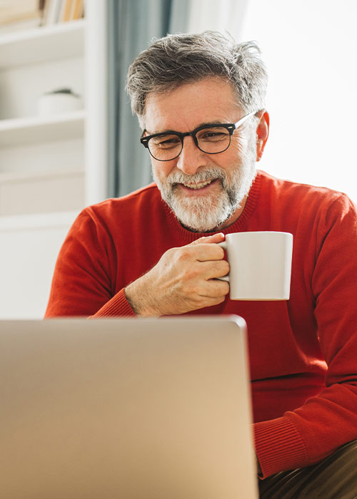 Geschäftsmann prüft am Laptop Finanzierungsoptionen und genießt eine Kaffeepause
