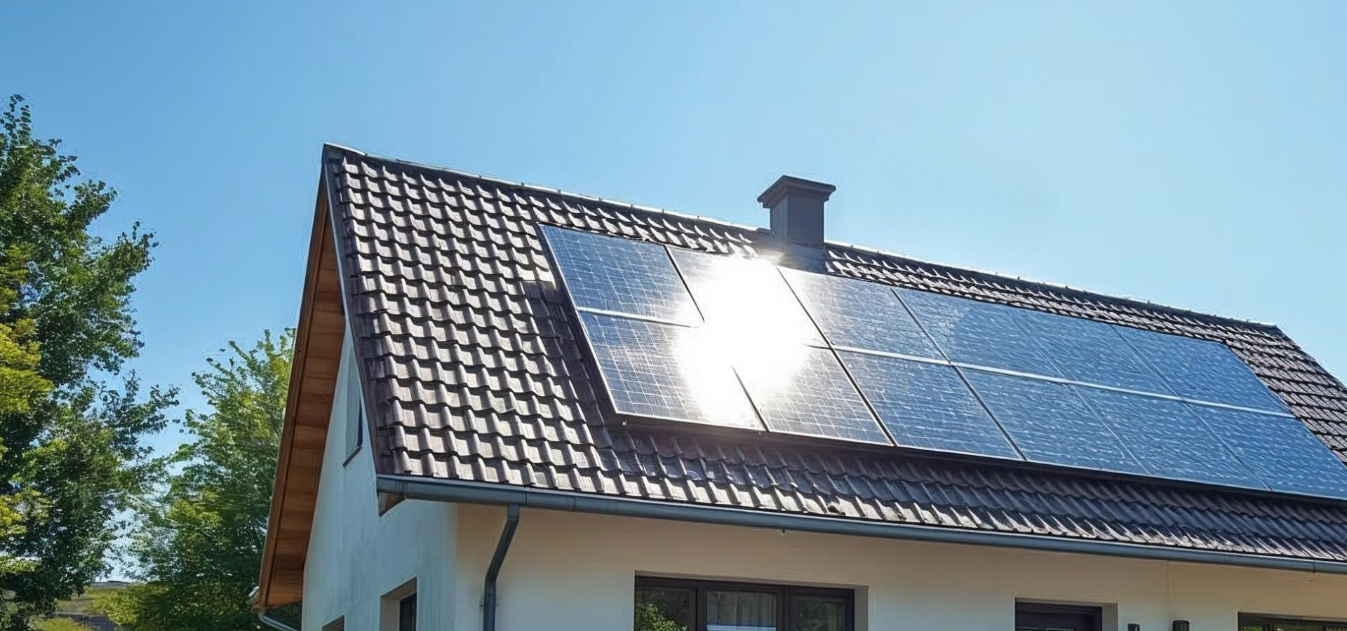 Einfamilienhaus mit schwarzem Satteldach, auf dem mehrere Solarmodule montiert sind, aufgenommen an einem sonnigen Tag.