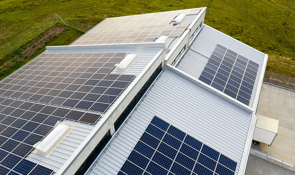 Luftaufnahme eines Industriegebäudes mit Photovoltaikanlage auf dem Dach für energieeffiziente Betriebsabläufe und nachhaltige Stromnutzung im Unternehmen.