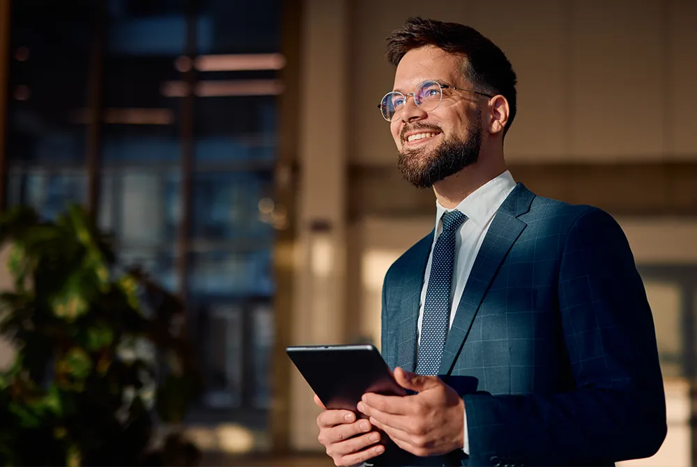 Geschäftsmann im Anzug hält ein Tablet und blickt zuversichtlich in die Zukunft dank der strategischen Investitionen in Photovoltaik und nachhaltiges Wachstum.