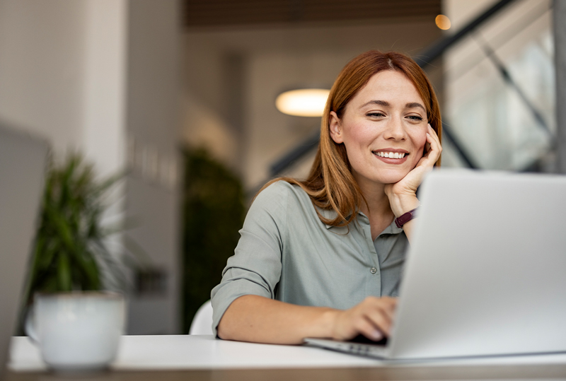 Geschäftsfrau informiert sich am Laptop über Finanzierungsmöglichkeiten in modernem Büro