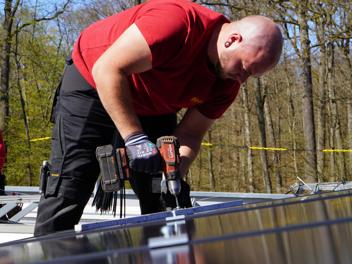 BSH Monteur mit Akkuschrauber, der Solarmodul befestigt