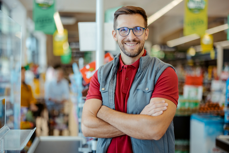 Mitarbeiter im Einzelhandel steht in einem Supermarkt mit hoher Beleuchtung und Energiebedarf
