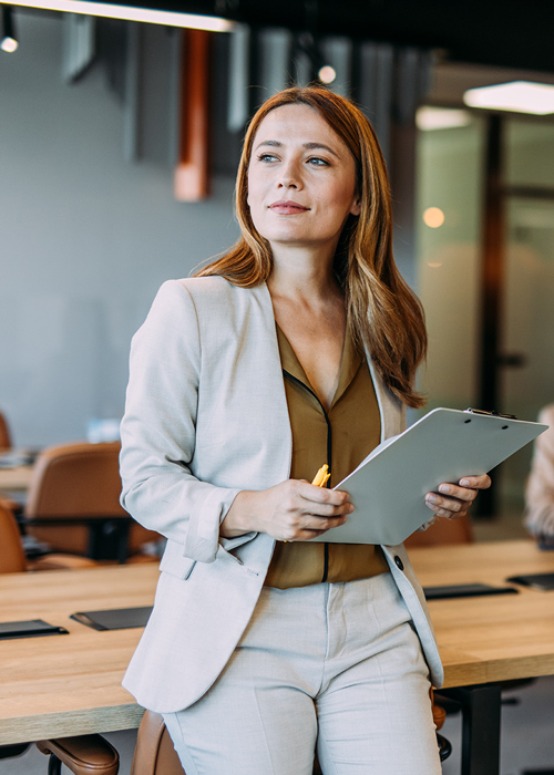 Unternehmerin steht im Büro und prüft Unterlagen zur Photovoltaikanschaffung.