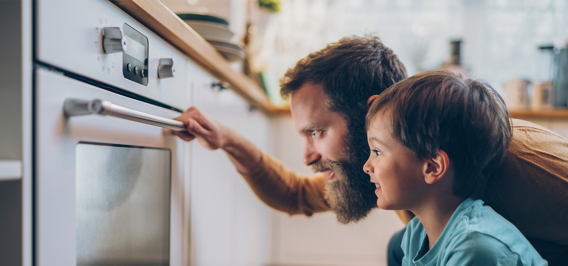 Ein Vater mit seinem Sohn schaut gespannt in den Backofen – Headerbild zum Ratgeber über dynamische Stromtarife.