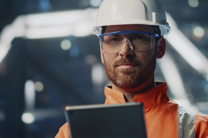 Unternehmensleiter mit Schutzhelm und Tablet informiert sich über Energieprojekte von BSH.